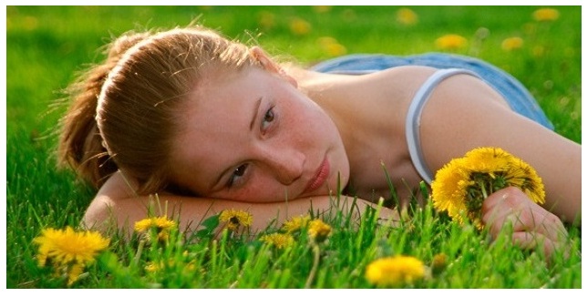 young girl lying in grass dandelions